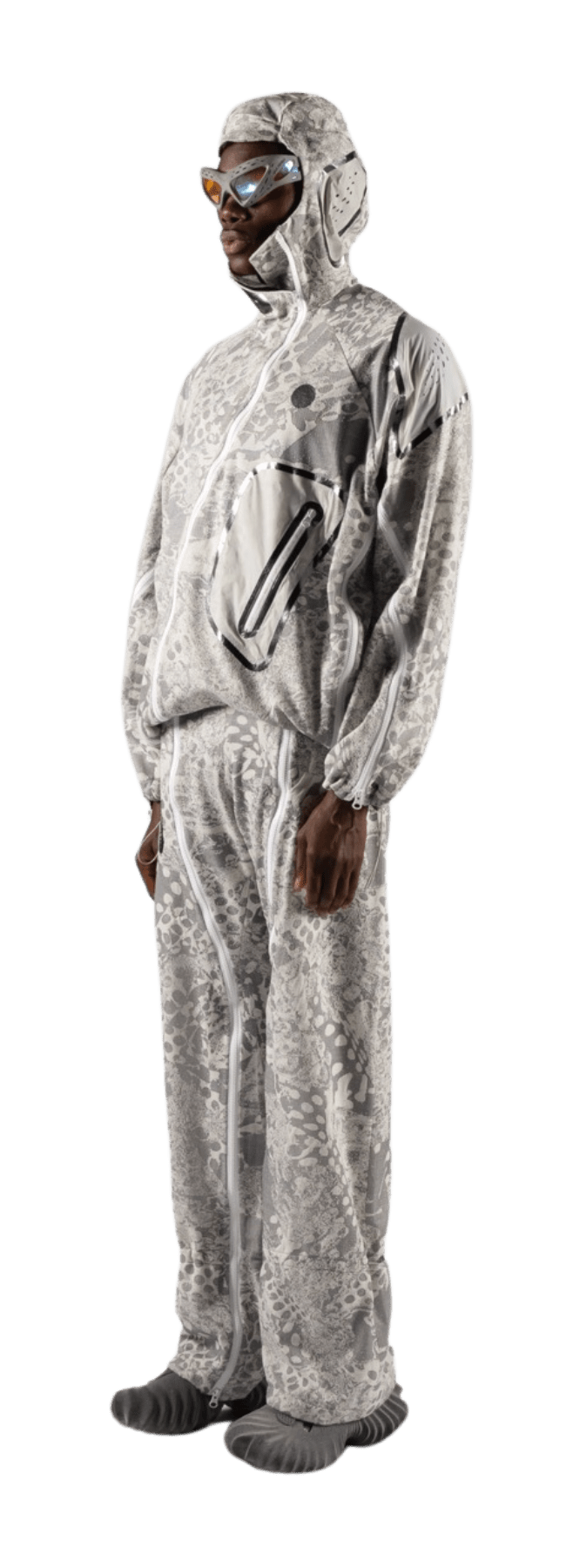 A person clad in a full-body suit crafted from luxurious Merino wool, featuring a sleek gray, patterned design complete with hood and goggles. The futuristic ensemble includes a large front pocket and matching pants as the individual stands against a plain background.
