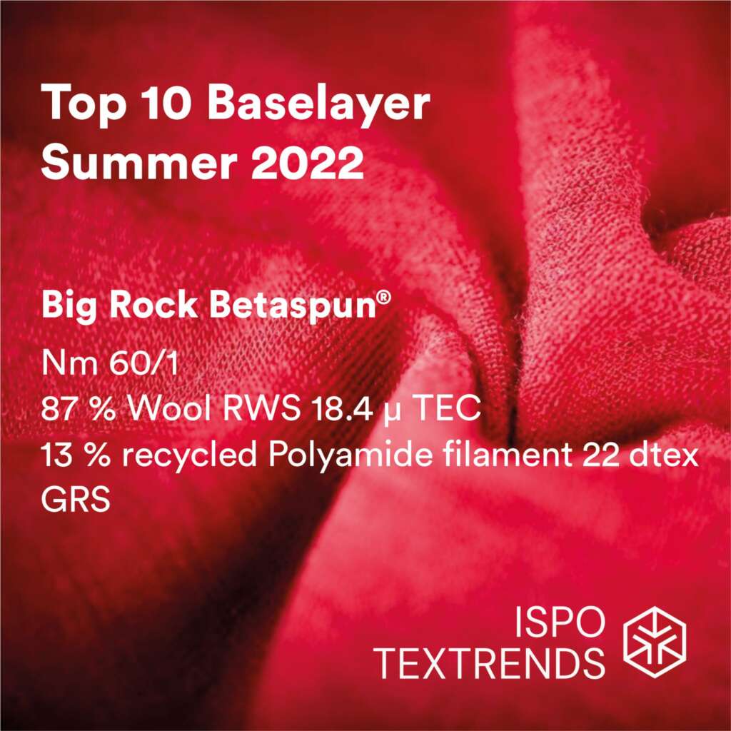 Close-up of red fabric with white text listing Top 10 Baselayer Summer 2022, fiber composition, and ISPO TEXTRENDS logo in the bottom right corner.
